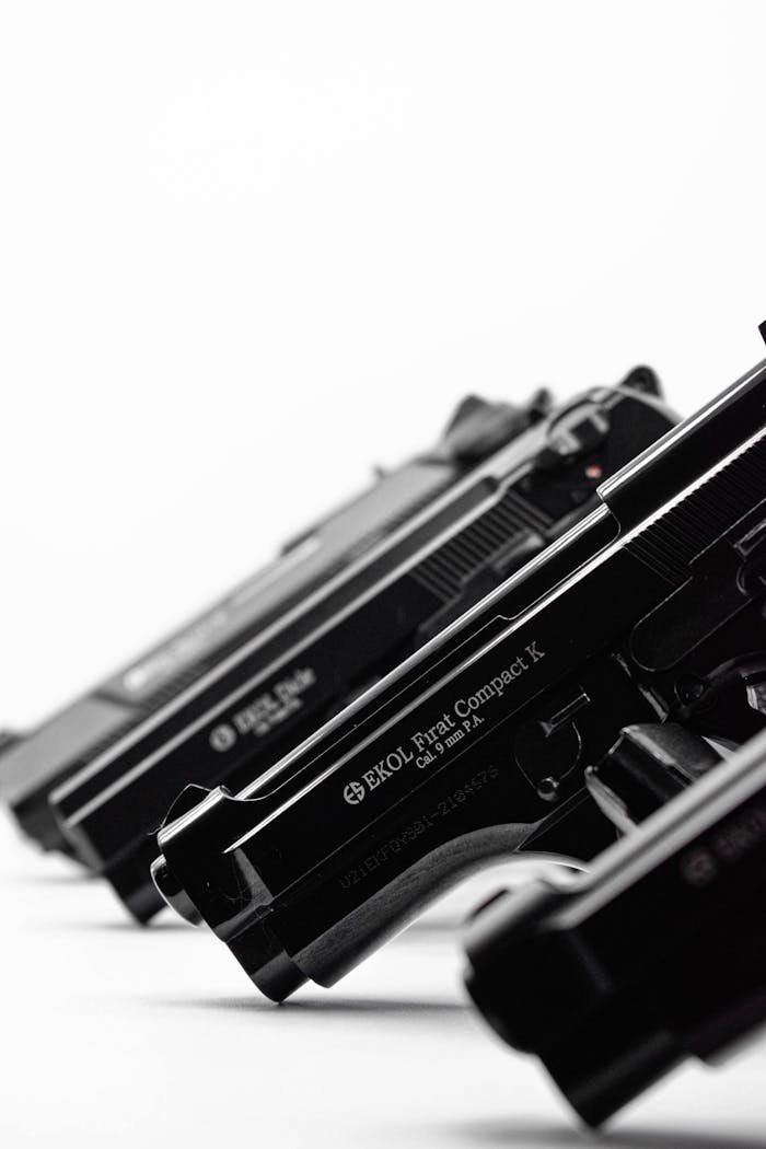 Monochrome image showcasing a lineup of handguns in a diagonal arrangement.