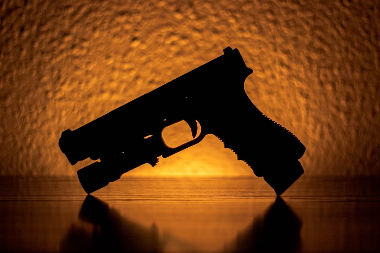Artistic silhouette of a handgun with a warm, textured background.