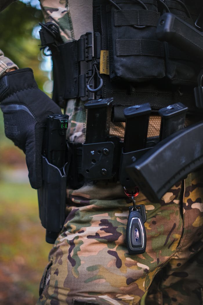 Close-up of a person in tactical gear and camouflage outfit outdoors.